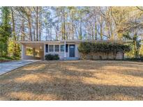 Ranch style home with gray brick exterior, attached carport, and landscaped lawn at 3701 Glen Mora Dr, Decatur, GA 30032