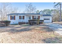 White house with brown shutters, front porch, and attached garage at 1506 Mcintosh Rd, Douglasville, GA 30134