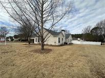 Beige house with gray roof, large backyard, and a tree in the front at 3454 Pleasant View Cir, Loganville, GA 30052