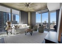 Bright living room featuring large windows with city views and a comfortable seating area at 855 Peachtree Ne St # 1703, Atlanta, GA 30308