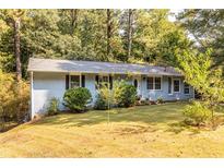 Ranch style home with blue painted brick exterior and landscaped yard at 2849 Crescendo Nw Dr, Atlanta, GA 30318