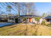 Ranch style home with brick facade, red door, and a well-manicured lawn at 2599 Browns Mill Se Rd, Atlanta, GA 30354