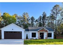 White farmhouse exterior with dark brown garage doors and a landscaped lawn at 1217 Eagles Nest Cir, Carrollton, GA 30116