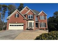 Brick two-story house with a three-car garage and well-manicured lawn at 2875 Factor Walk Blvd, Suwanee, GA 30024