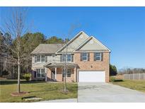 Two-story house with brick and siding exterior, white garage door, and landscaped lawn at 4205 Woodsley Pl, Loganville, GA 30052