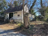 Exterior of a run-down, one-story house with a wooden porch and overgrown landscaping at 125 Martin Se Ave, Atlanta, GA 30315