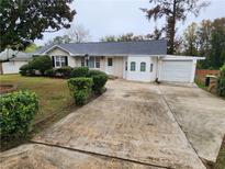 Brick ranch house with a gray roof, landscaping, and a long driveway at 2614 Lilac Dr, Morrow, GA 30260