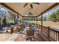 Inviting covered deck featuring wood plank flooring, ceiling fans, and an outdoor dining area perfect for entertaining at 2230 Mcbrayer Ct, Cumming, GA 30028