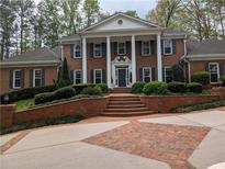 Stately brick home with white columns, dark shutters, and professionally landscaped front yard at 1120 Heards Ferry Rd, Sandy Springs, GA 30328