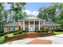 Brick home with columns, lush landscaping, and brick driveway at 1120 Heards Ferry Rd, Sandy Springs, GA 30328