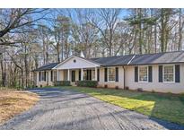 Charming one-story brick home with a well-maintained lawn and a long driveway nestled among mature trees at 414 Dogwood Dr, Canton, GA 30114
