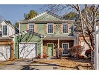 Two-story townhome with green siding, stone accents, and a two-car garage at 6269 Colonial Vw, Fairburn, GA 30213