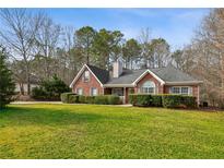 Charming brick home featuring a well-manicured lawn and mature landscaping at 300 Huntington St, Covington, GA 30016