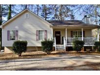 House exterior featuring a beige vinyl sided home with a front porch and landscaping at 6086 Woodstock Rd, Acworth, GA 30102