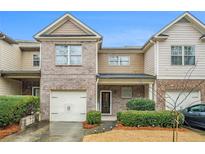 Charming townhome with brick and siding exterior, attached garage, and well-maintained landscaping at 1328 Stone Bay Sw Dr, South Fulton, GA 30331