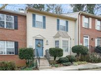 Two-story brick townhouse with blue door, landscaping, and steps leading to the entrance at 6412 Wedgeview Dr, Tucker, GA 30084