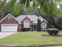 Brick house with a white garage door and a well-manicured lawn at 3957 Birdie Dr, Douglasville, GA 30134