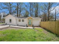 Charming white house with a green door, landscaped yard, and wooden fence at 1685 Harbin Sw Rd, Atlanta, GA 30311