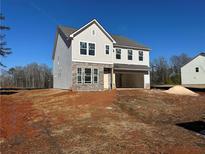 Two-story house with gray siding and stone accents, attached garage, and landscaping at 7293 Eton Ln, Locust Grove, GA 30248