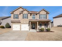 Brick two-story house with a three-car garage and landscaping at 7705 Sylvaner Ln, Atlanta, GA 30349