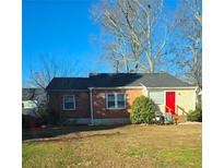 Brick ranch house with red door, front yard, and mature trees at 122 Martha Ne Ave, Atlanta, GA 30317