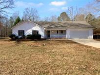 Charming one-story house with a white exterior, covered porch, and attached garage at 220 Mountain Way, Covington, GA 30016