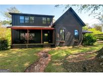 Dark-colored two-story house with a porch and brick pathway at 5152 Worsham Ne St, Covington, GA 30014