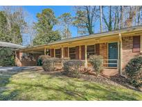 Brick ranch house with carport, mature shrubs, and a well-manicured lawn at 1276 Hickory Sw Dr, Lilburn, GA 30047