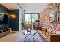 Spacious living room with exposed brick wall, large windows, and leather furniture at 800 Peachtree Ne St # 8429, Atlanta, GA 30308