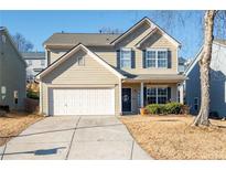 Two-story house with beige siding, a white garage door, and a landscaped yard at 311 Tuggle Ct, Woodstock, GA 30188