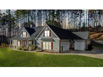 Two story house with gray siding, a large front porch, and a three car garage at 607 Walker Ct, Canton, GA 30115