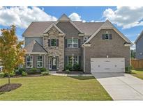 Two story home with gray brick and stone accents, three car garage, and manicured lawn at 4259 Hansford Loop, Marietta, GA 30064