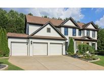 Beautiful two story home showcasing a well manicured lawn, brown roof, and a three car garage at 334 Spotted Ridge Cir, Woodstock, GA 30188