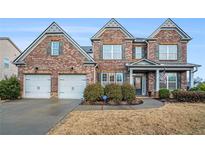 Brick two-story house with a two-car garage and manicured lawn at 4910 Wagon Trl, Cumming, GA 30028