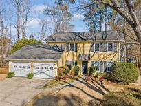 Attractive two-story yellow house with a two-car garage and manicured landscaping at 585 Tyson Knls, Roswell, GA 30076