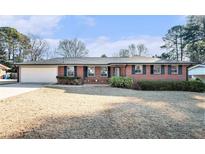 Charming brick home with an attached garage and a well-manicured front lawn under a sunny sky at 3089 Ranlo Dr, Atlanta, GA 30340