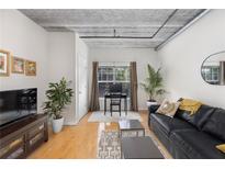 Bright living room features hardwood floors, exposed ductwork, and a comfy black couch at 800 Peachtree St # 1112, Atlanta, GA 30308