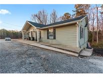 Ranch style home with gray siding, a covered entry, and a spacious front yard at 4955 R H Smith Blvd, Sugar Hill, GA 30518