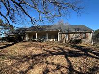 Brick ranch house with covered porch and mature trees at 144 Rockbridge Sw Rd, Lilburn, GA 30047