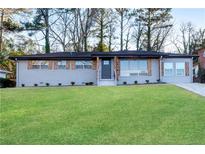 Newly renovated ranch home with gray brick, wood accents, and a landscaped lawn at 2933 Edna Ln, Decatur, GA 30032