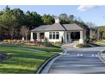 View of the gated entrance to a community with pristine landscaping, mature trees, and well-maintained asphalt at 423 Southland Cir, Canton, GA 30115