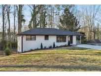 Charming ranch home with white brick exterior, updated landscaping, and a spacious driveway at 1120 Starline Se Dr, Smyrna, GA 30080