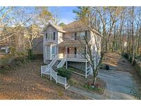 Two-story house with light beige siding, a wraparound porch, and a white railing at 2618 Windage Sw Dr, Marietta, GA 30008