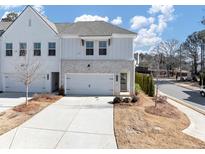 Two-story townhome with white brick exterior, two-car garage, and landscaping at 3576 Silvery Way, Powder Springs, GA 30127