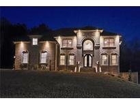 Stunning two-story brick home featuring an elegant arched entryway and nighttime illumination at 3317 Steeple Chase Way, Conyers, GA 30094