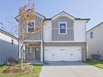 Two-story house with gray and white siding, a three-car garage, and a manicured lawn at 2034 Avalon Rdg, Conyers, GA 30013