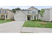 Charming two-story home features a well-manicured lawn and a paved driveway leading to a two-car garage at 386 Rock View Ln, Covington, GA 30016