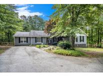 Gray house with stone accents, wood-trimmed windows, and a landscaped yard at 675 Mayes Rd, Powder Springs, GA 30127
