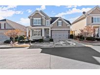 Charming two-story home featuring a well-manicured front yard and an attached two-car garage at 124 Heron Xing, Woodstock, GA 30188