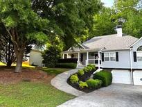 Charming home featuring a welcoming front yard, lush landscaping, and attached two-car garage at 213 Moore Valley Way, Canton, GA 30115
